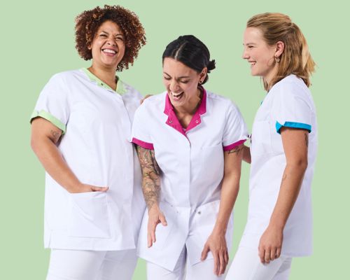 Drei Pflegerinnen sind in weißer Arbeitskleidung eingekleidet mit verschieden farbigen Streifen.